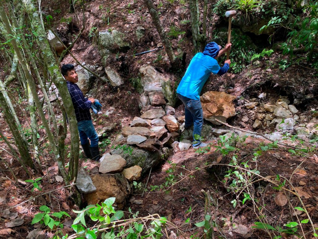 hombres trabajando haciendo un dique de piedra